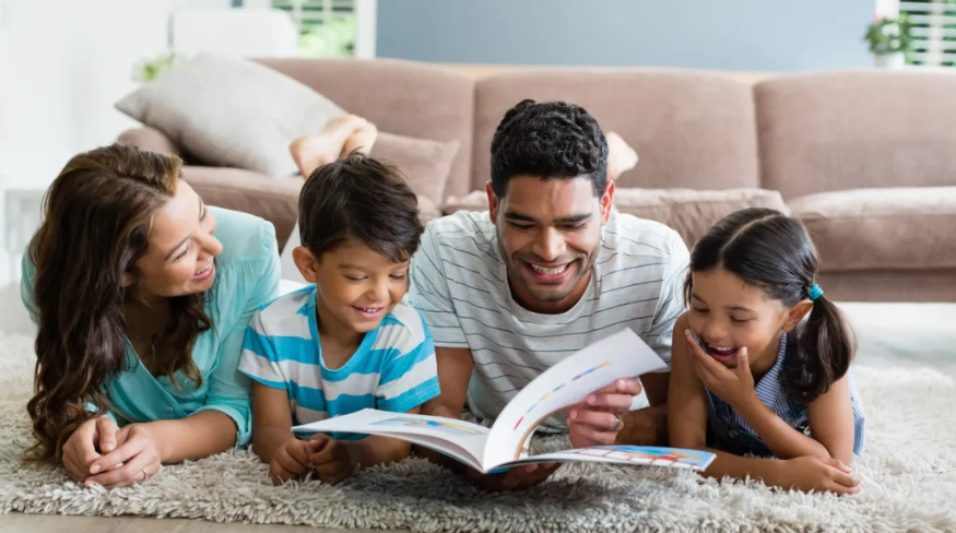 Family reading a book together in the living room.