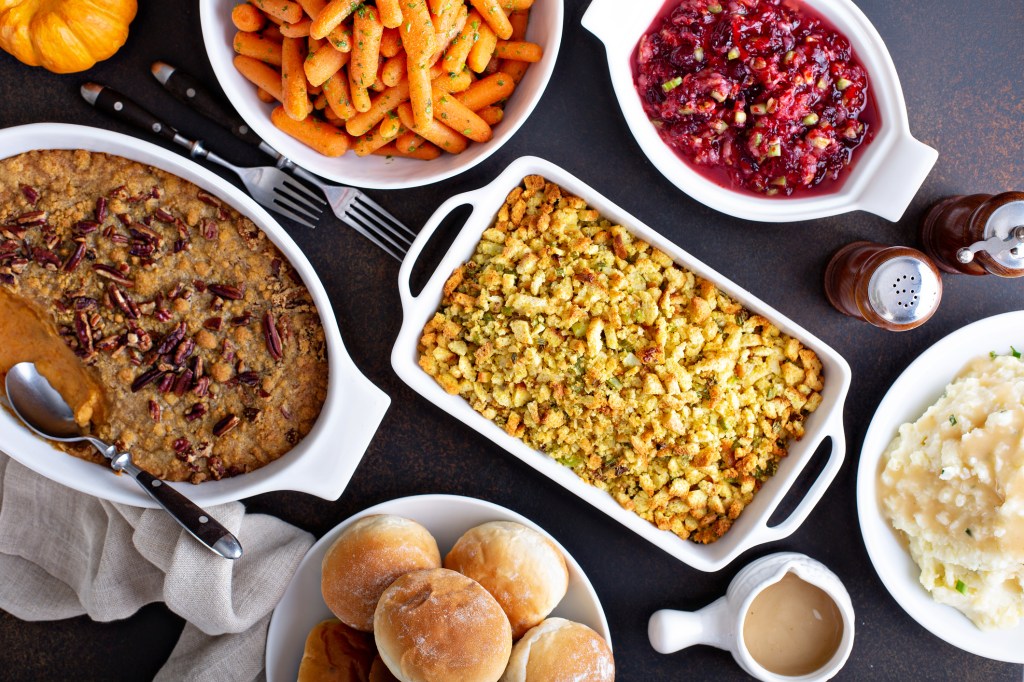 Variety of Thanksgiving sides on the dinner table, carrots, mashed potatoes, sweet potato casserole and stuffing