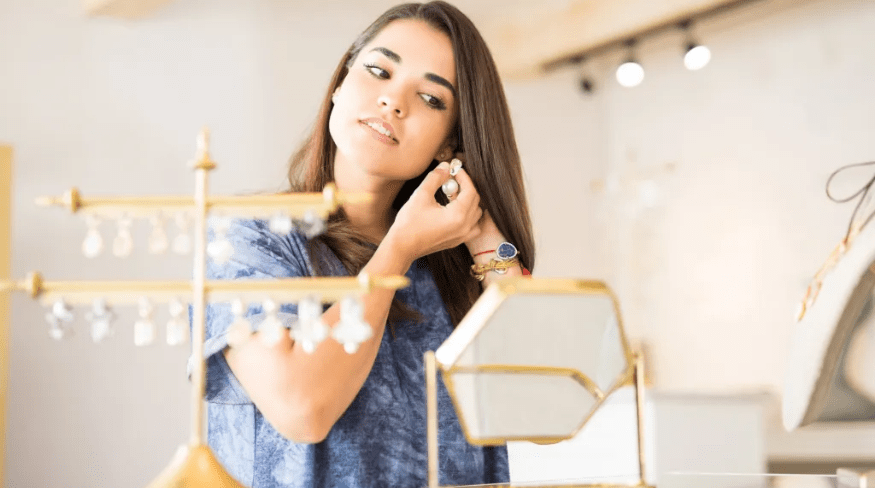 Young girl putting on earrings at a jewelry store.
