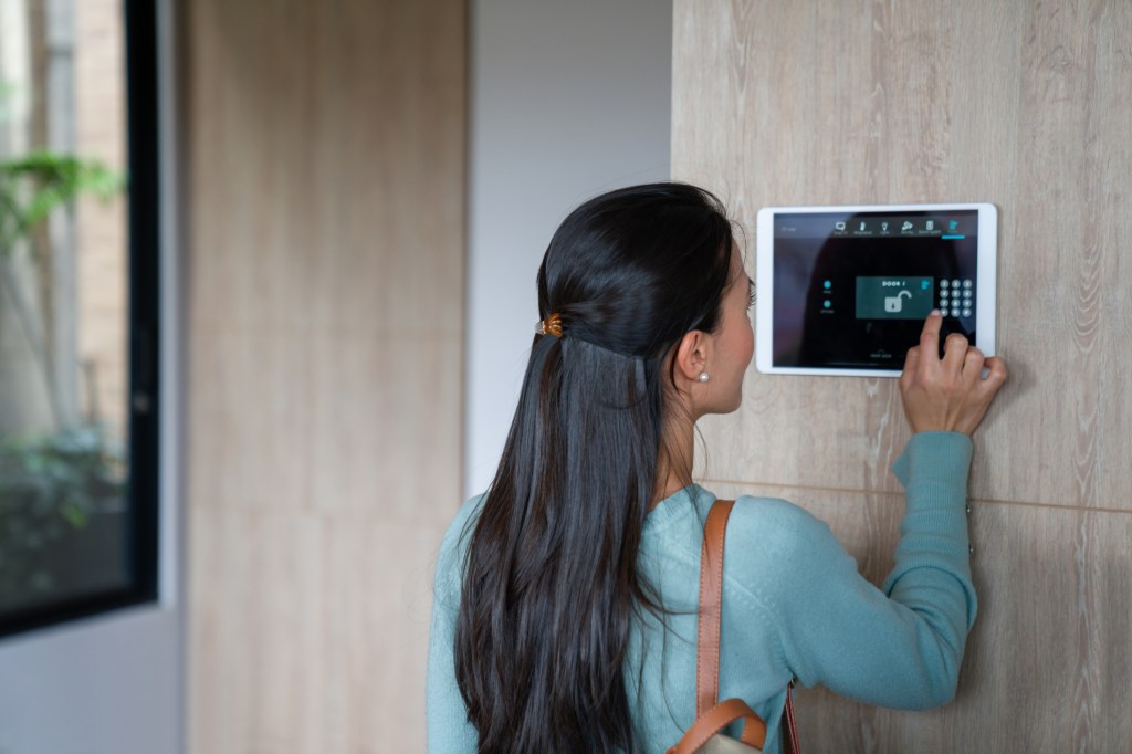 Woman entering pin to lock the door of her house using a home automation system