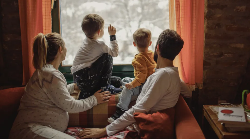 Family looking at snow falling outside.