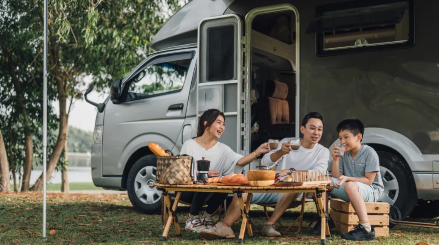 A family having a picnic outside a camper trailer.
