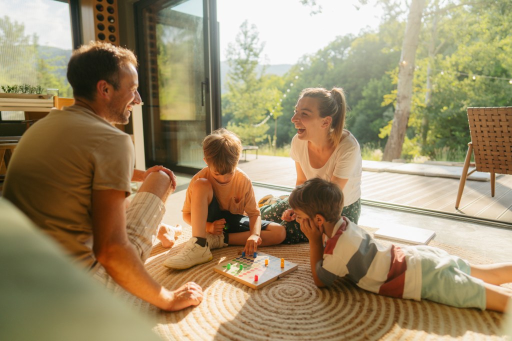 Photo of a young family playing board games together on the floor of their home.