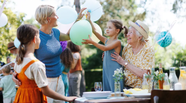 Grandmother, mother and daughter setting decorations for summer garden party.