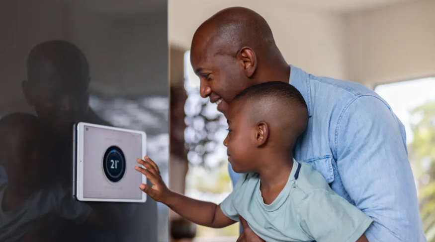 Father and son using a home automation system to lower the temperature of their house.
