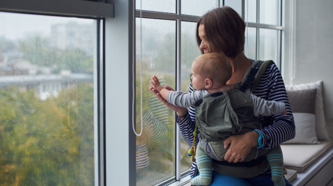 Mother and baby looking out side at the rain.